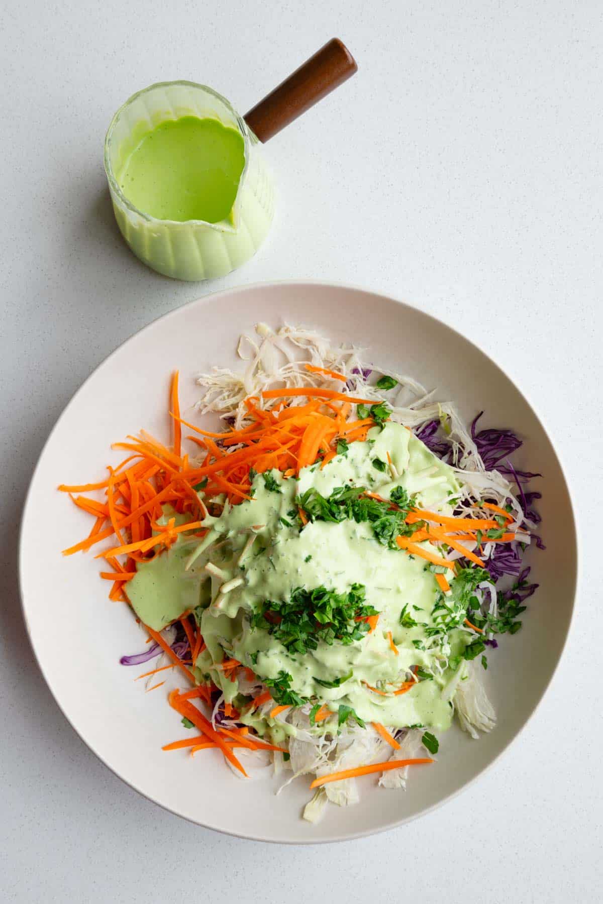 Red cabbage coleslaw topped with a drizzle of creamy green goddess mayo-free dressing.
