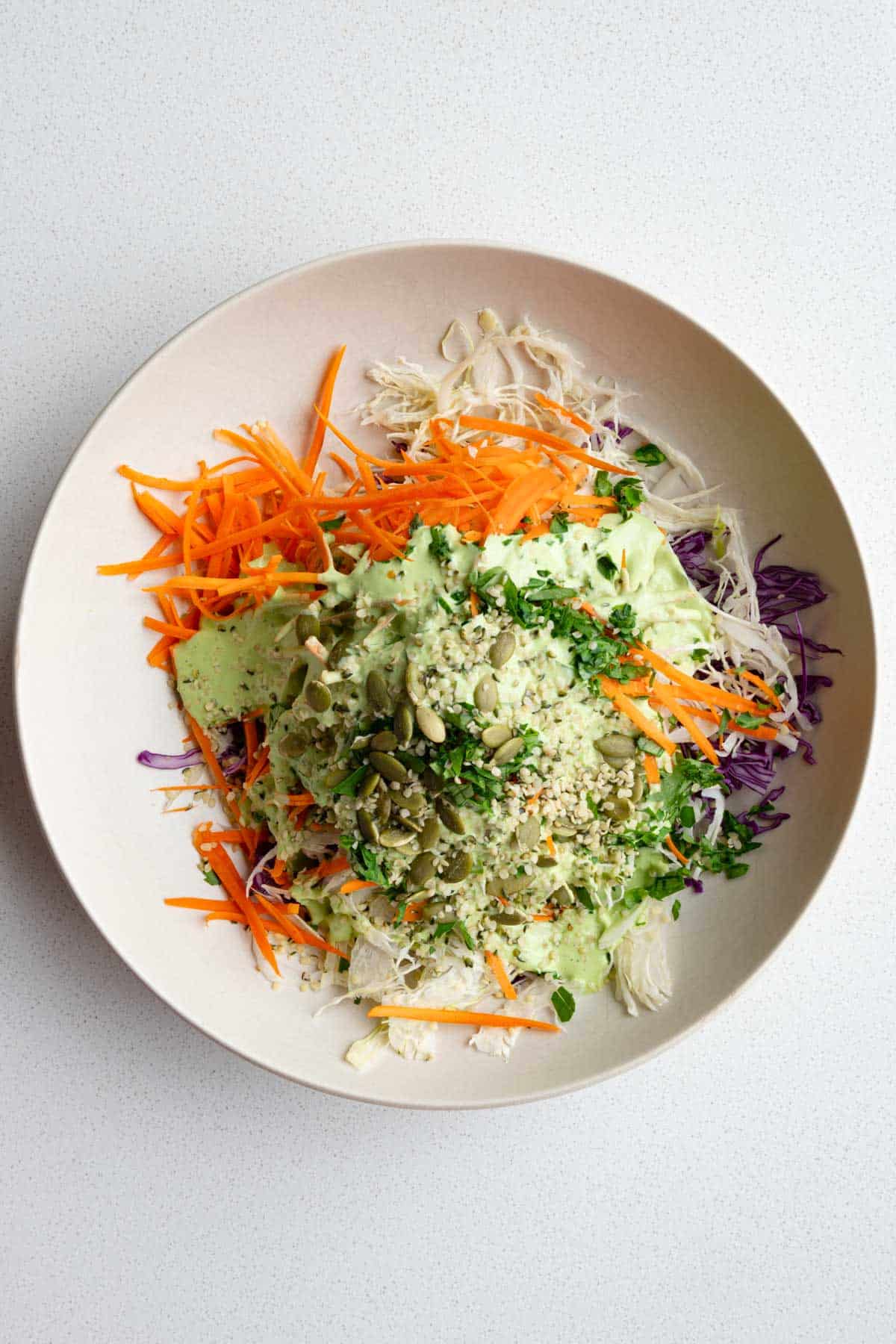 Red cabbage coleslaw with a drizzle of creamy mayo-free dressing on top.