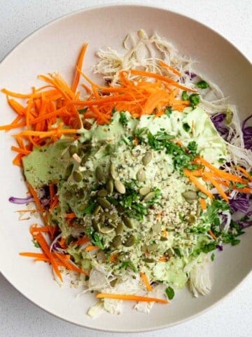 Red cabbage coleslaw with a drizzle of creamy mayo-free dressing on top.