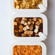 Three tofu marinades in meal prep containers with grated tofu, cubed tofu, and thinly sliced tofu.