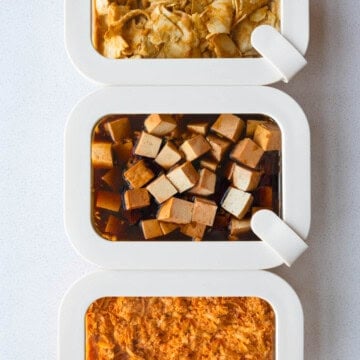 Three tofu marinades in meal prep containers with grated tofu, cubed tofu, and thinly sliced tofu.