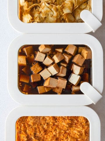 Three tofu marinades in meal prep containers with grated tofu, cubed tofu, and thinly sliced tofu.