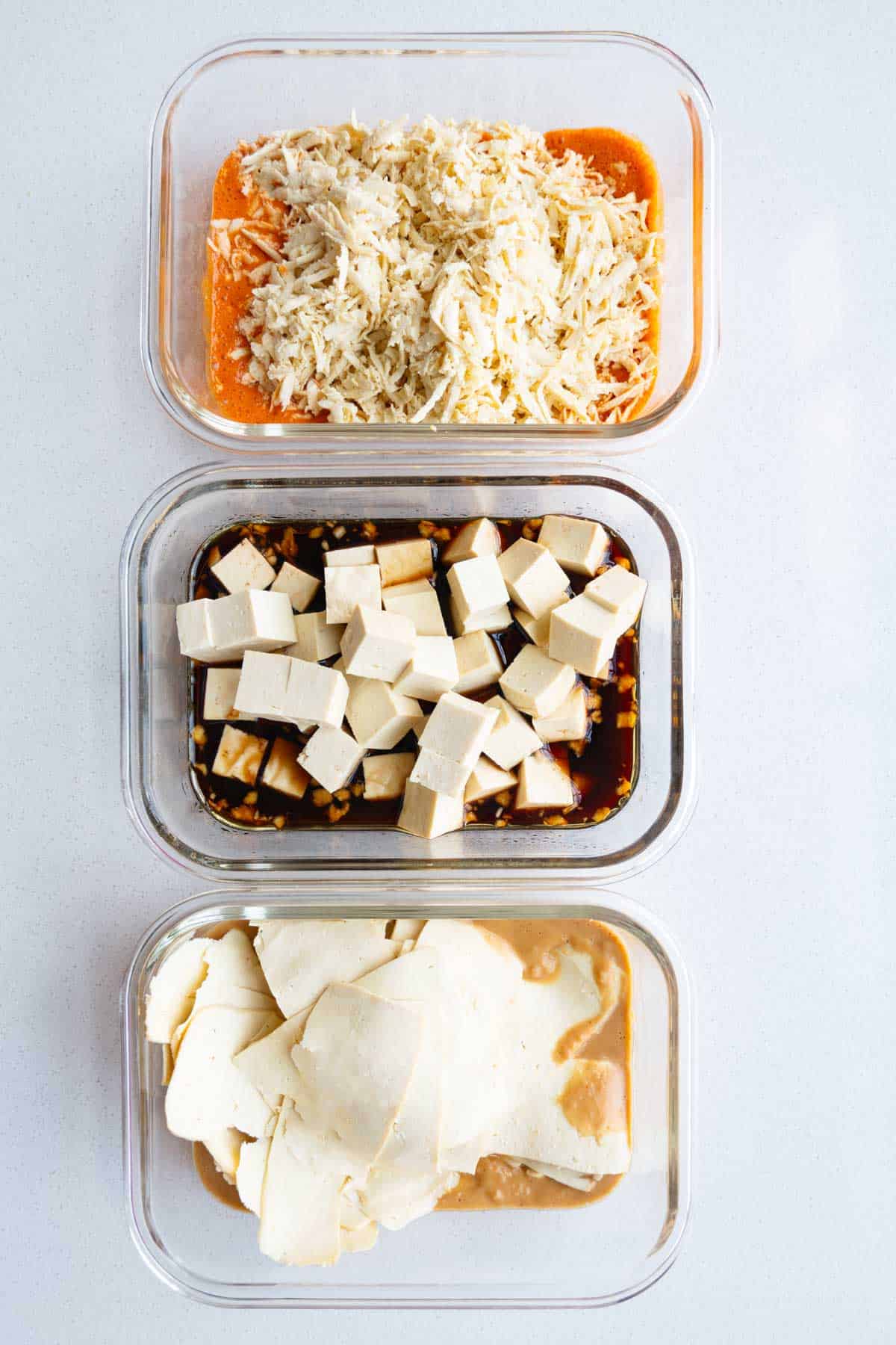 Grated, peeled, and sliced tofu on top of three marinades.