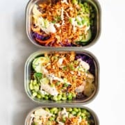 Vegan sushi bowl with cabbage, carrot, cucumber, edamame, 7-grain blend, seaweed, pickled ginger, sesame seeds, scallions, baked grated tofu, and sushi sauce.