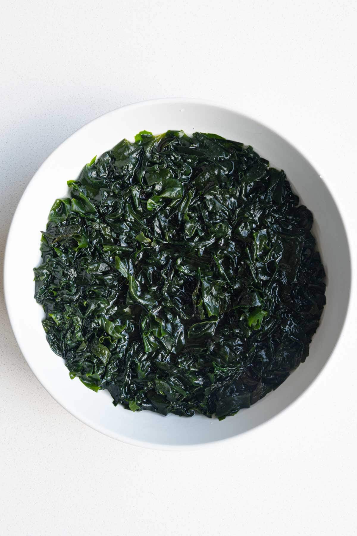 Soaked wakame seaweed in a white bowl.