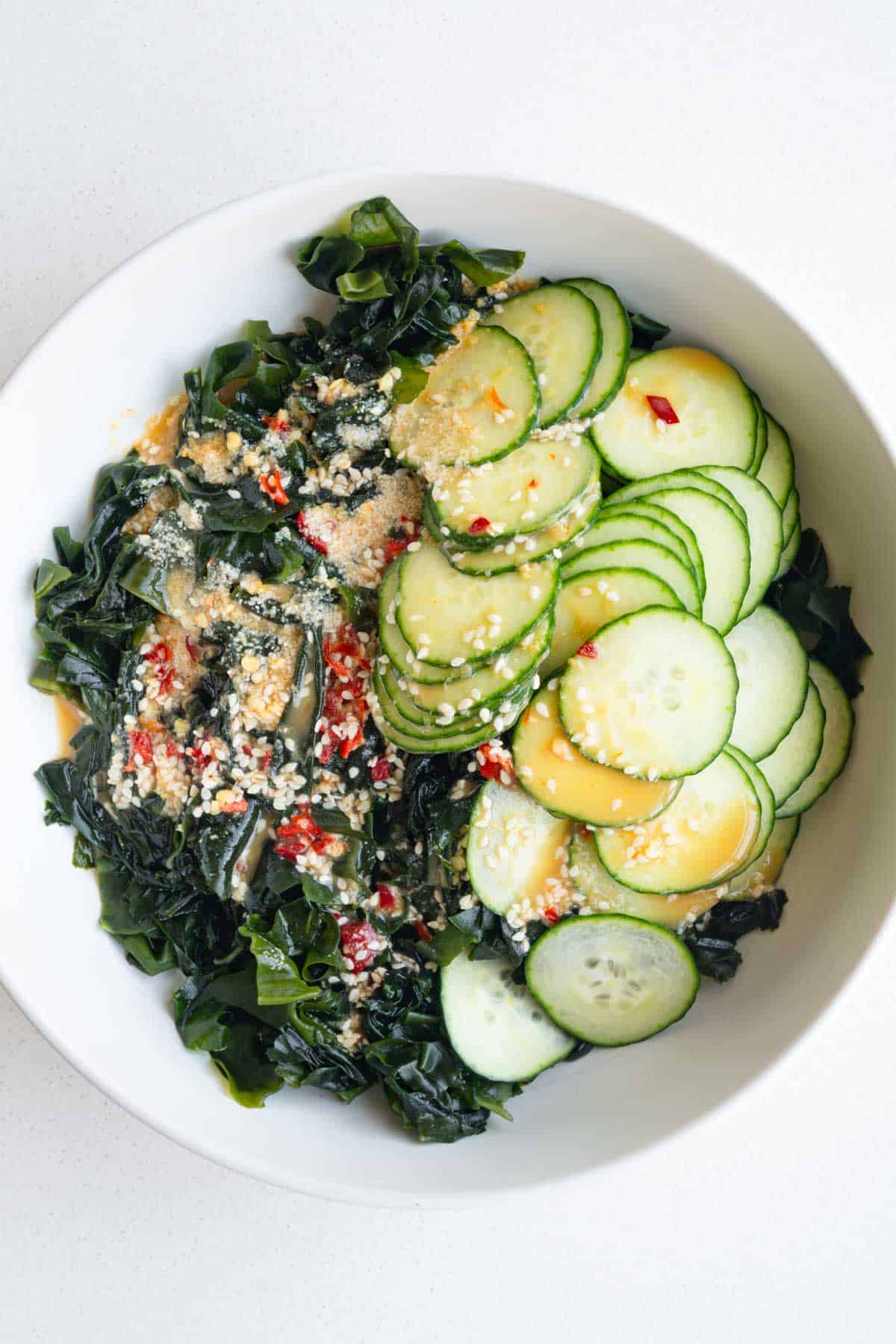 Dressing on top of sea vegetables and sliced cucumber.