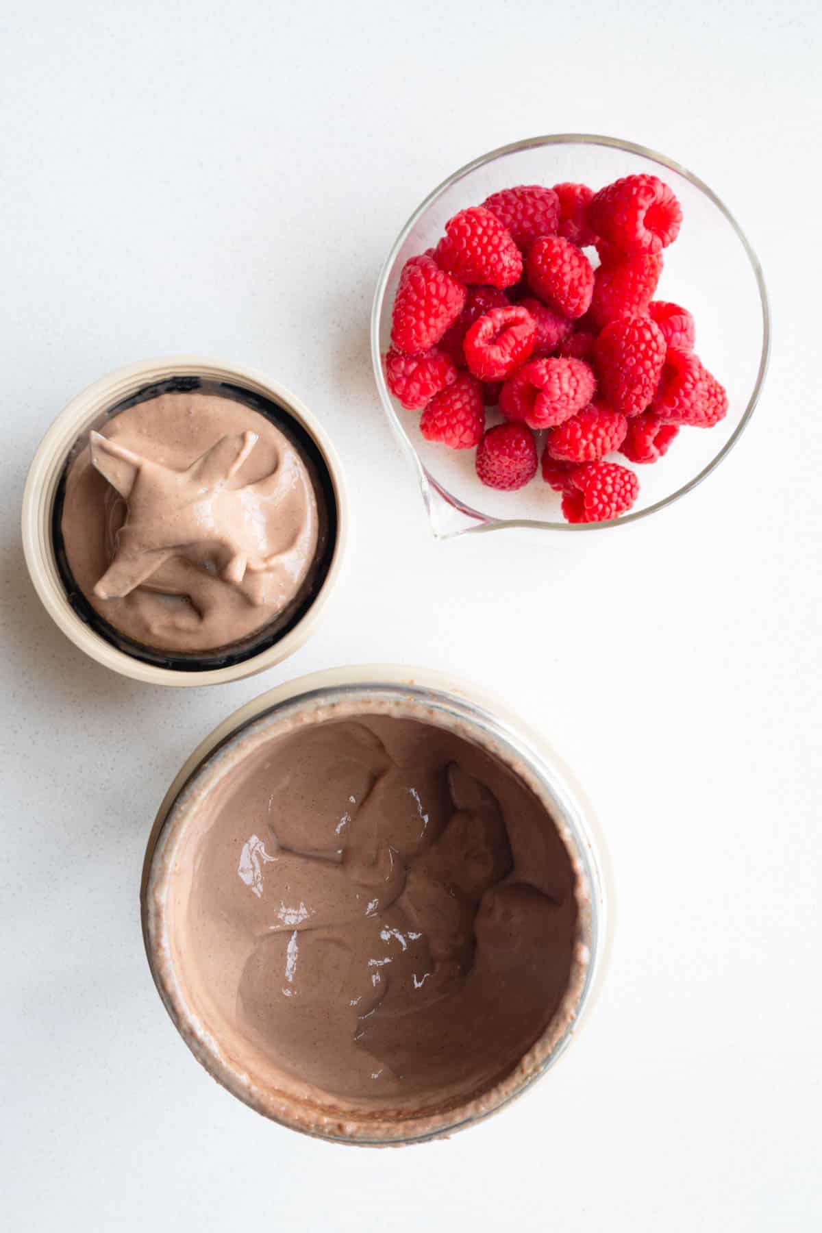 Blended healthy chocolate mousse in a blender canister with raspberries.