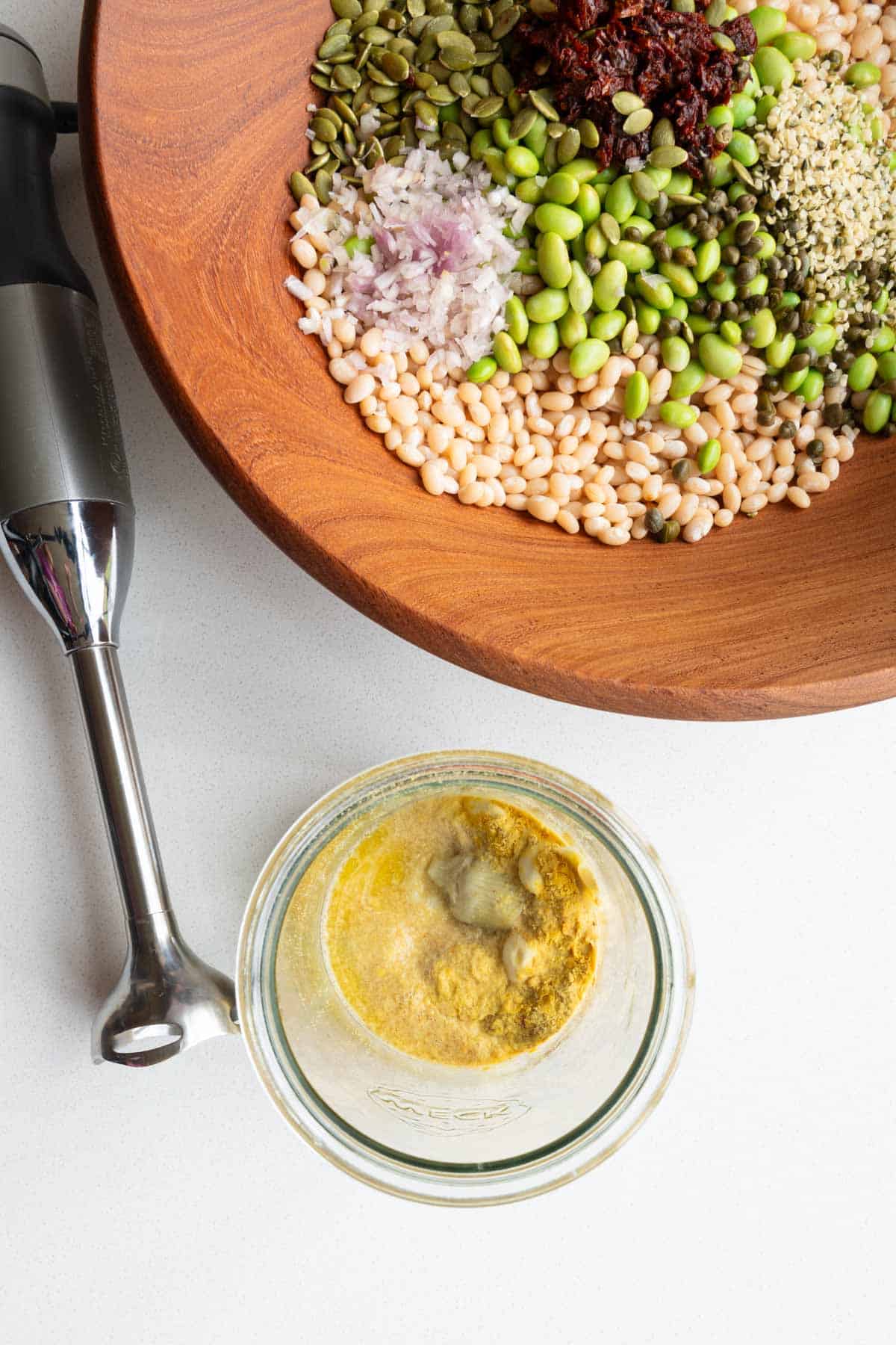 Pumpkin seeds, edamame, white beans, capers, sun-dried tomatoes, shallots, and dressing ingredients with an immersion blender.