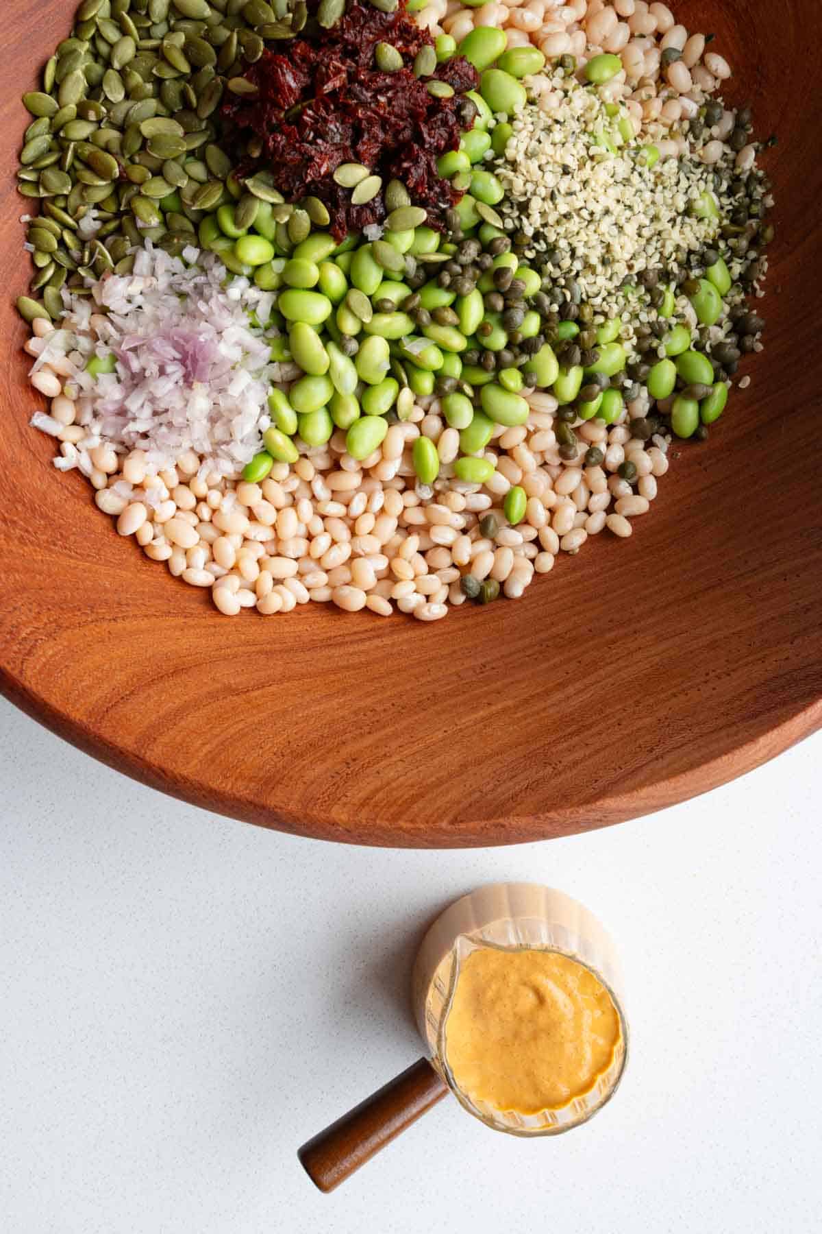 White beans, pumpkin seeds, sun-dried tomatoes, edamame, shallots, hemp hearts, capers, and harissa dressing.