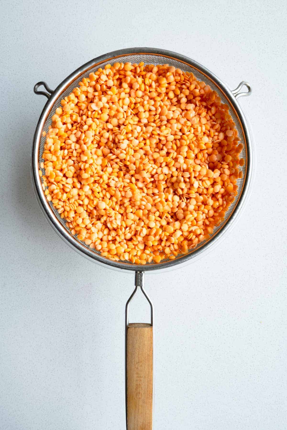 Drained red lentils in a sieve.