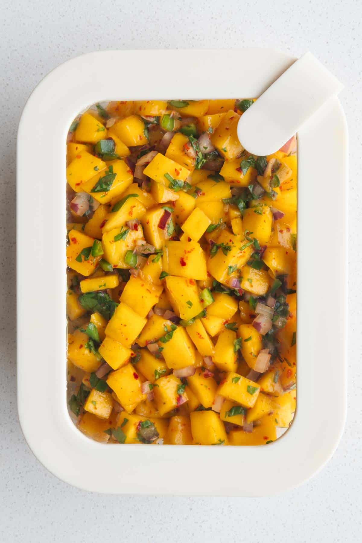 Mango salsa stored in a glass container.