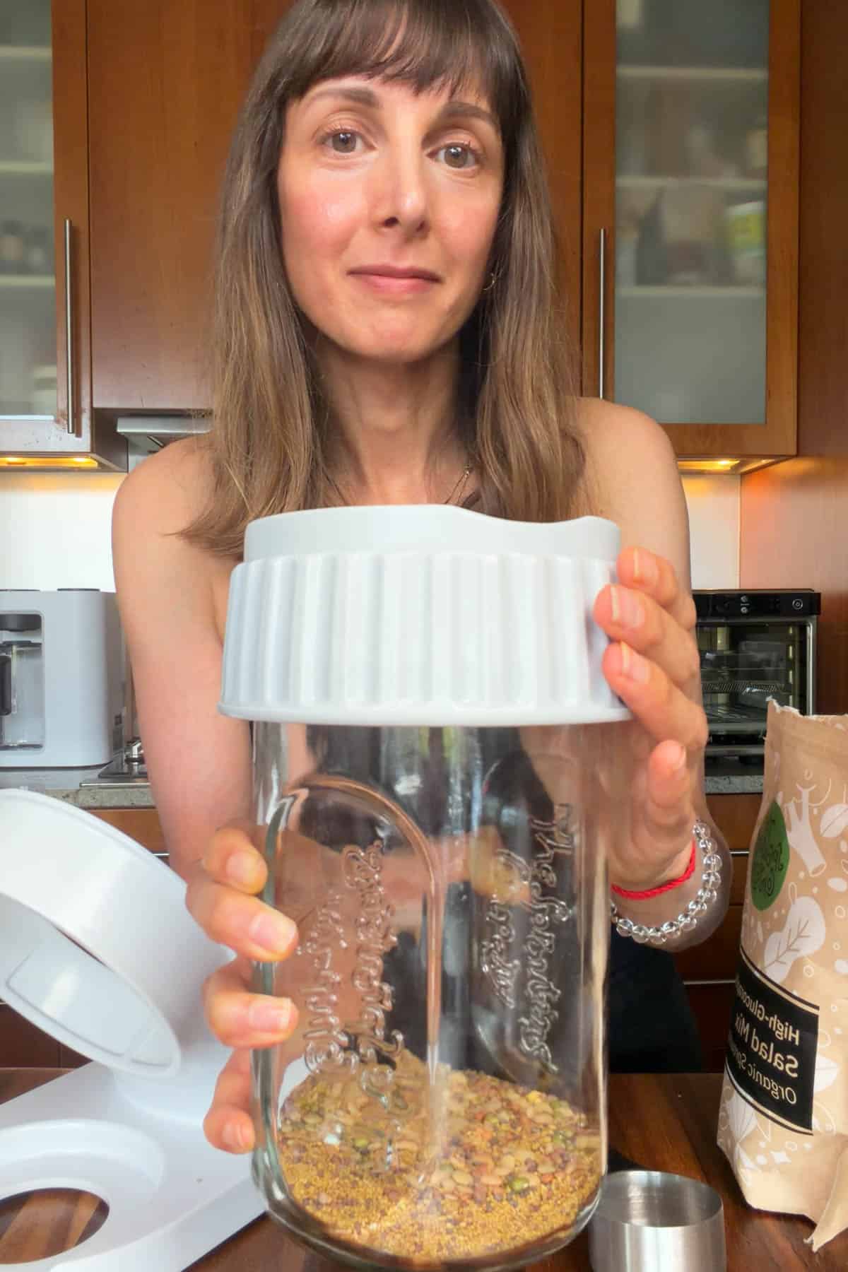 Nisha holding a sprouting jar with high-glucoraphanin sprout seed salad mix.