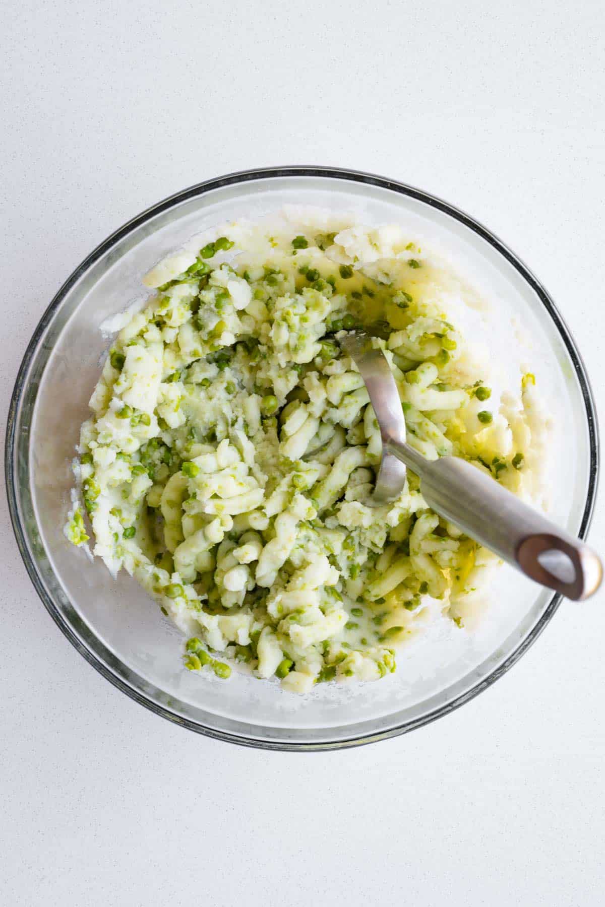Mashed green peas and potatoes in a glass bowl.