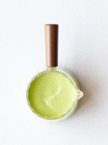 Creamy oil-free pumpkin seed dressing in a glass pouring container.