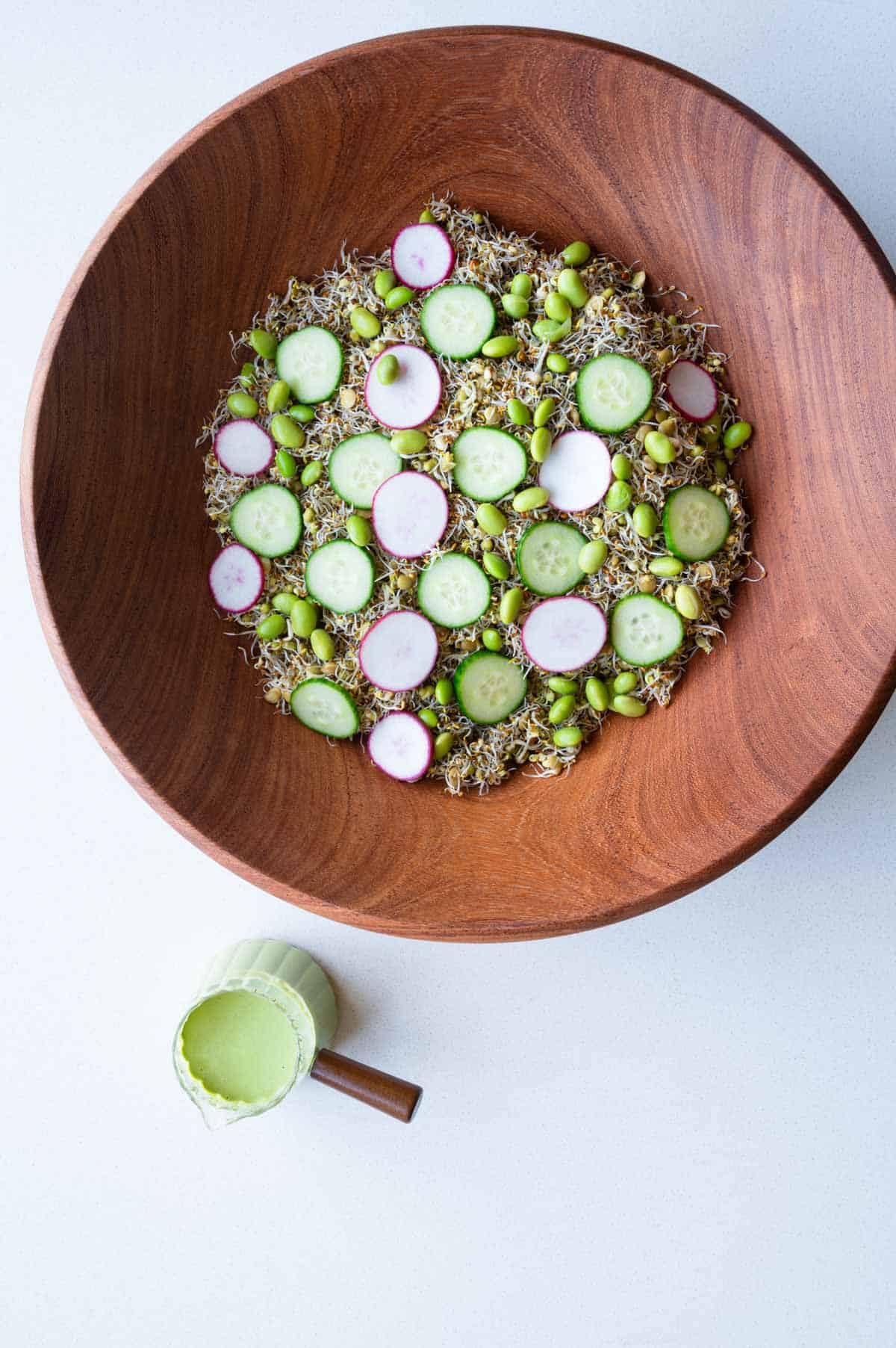 Sprouted seeds salad with cucumber, edamame, and radishes with creamy pumpkin seed dressing.