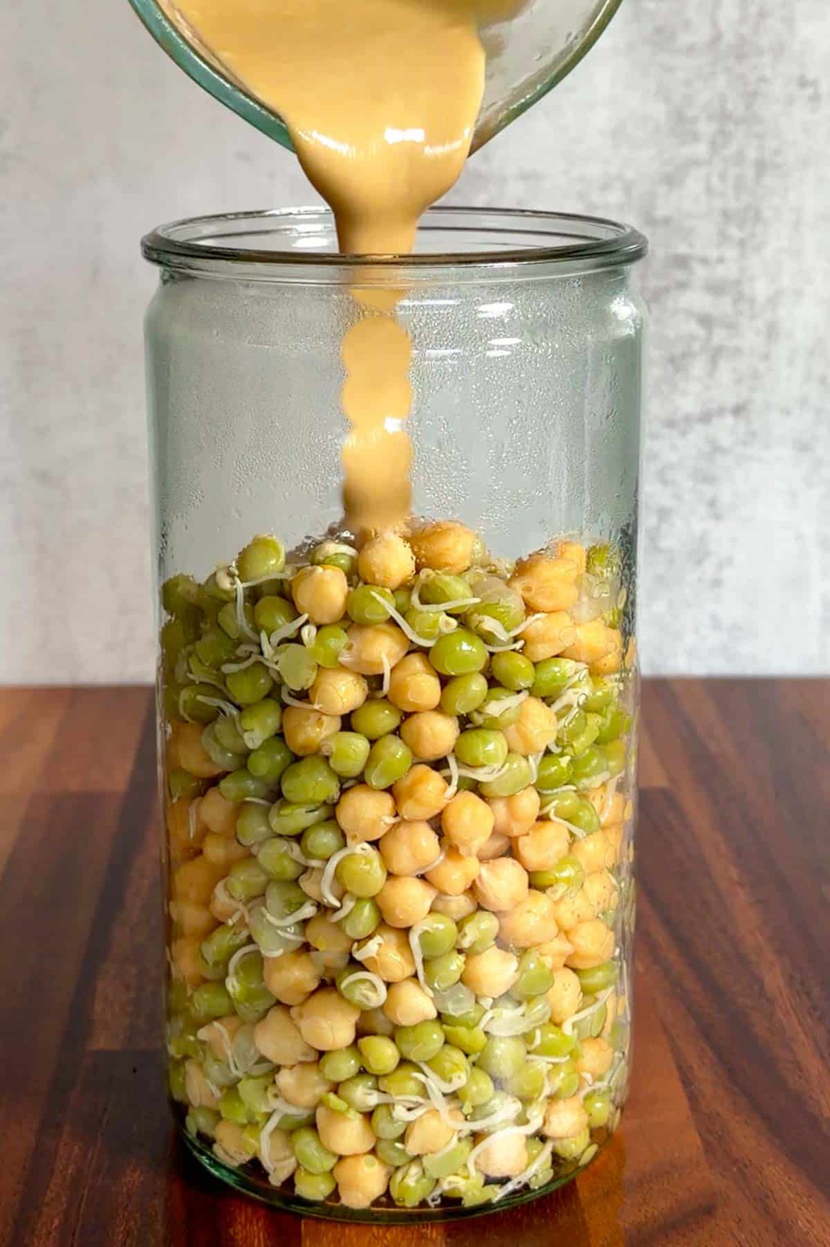 Sprouted peas and chickpeas in a jar with tahini for making hummus.