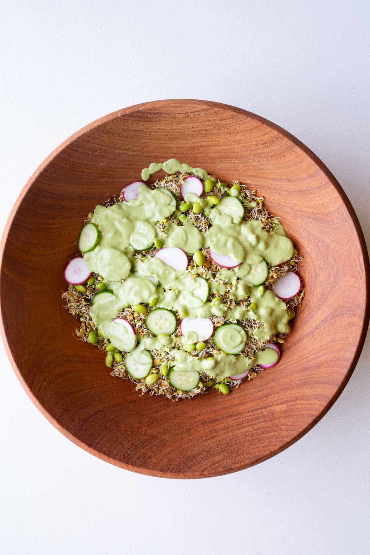 Sprouted seeds salad with edamame, cucumber and radishes topped with creamy pumpkin seed dressing.