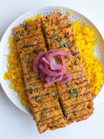 Sheet-pan vegan kebabs on yellow rice with pickled red onion.
