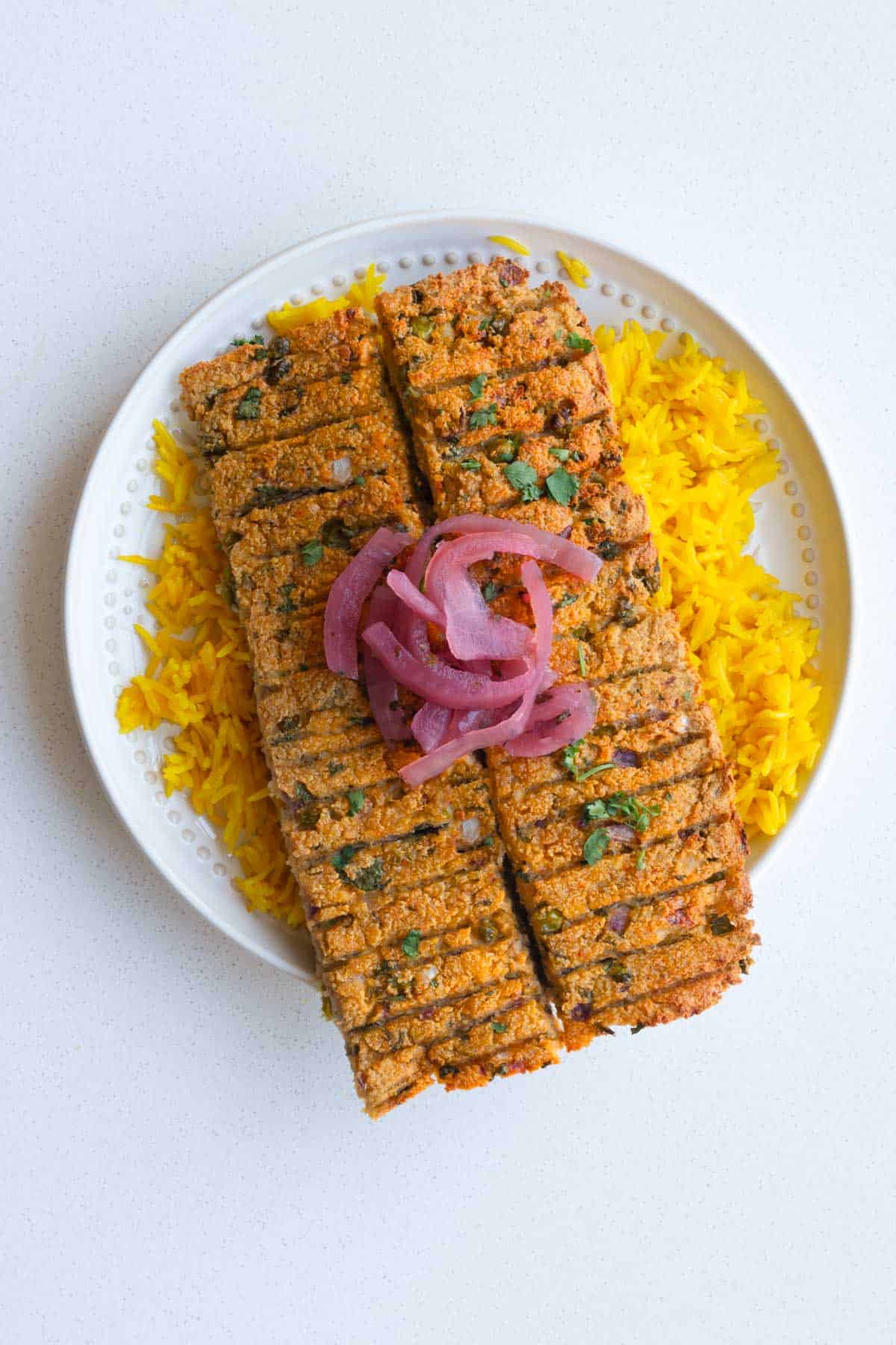Sheet-pan vegan kebabs on yellow rice with ketchup and pickled red onion.