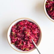 Beetroot salad with pomegranate in a bowl with a fork.