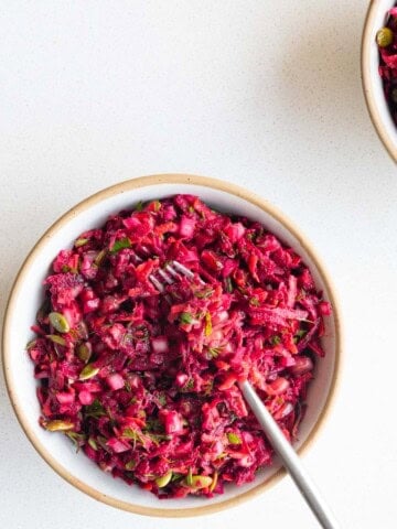 Beetroot salad with pomegranate in a bowl with a fork.
