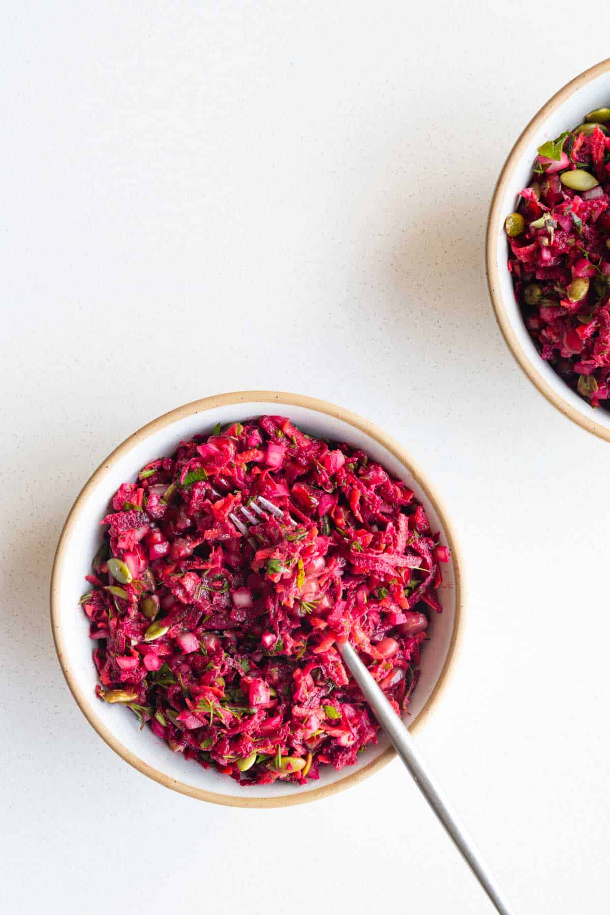 Beetroot salad with pomegranate in a bowl with a fork.