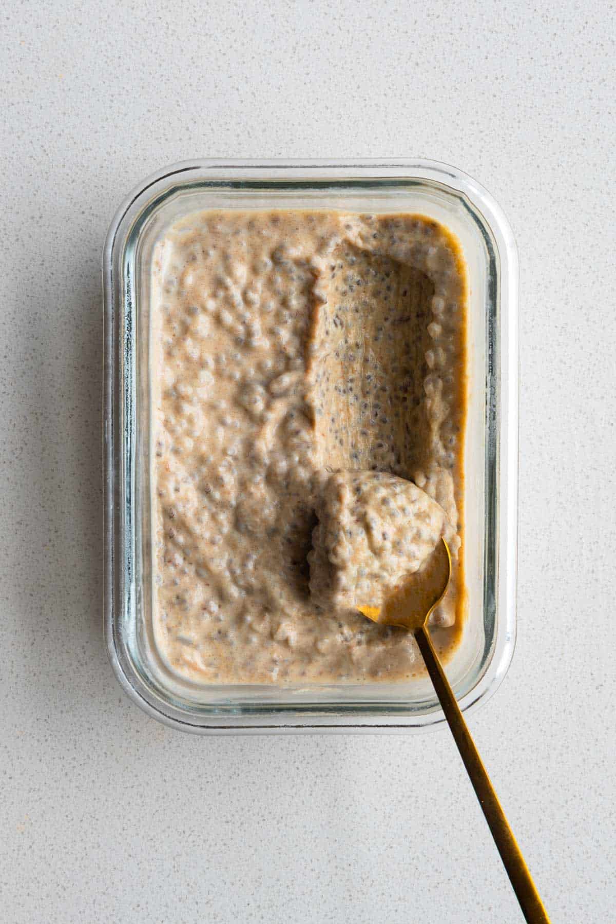 Chia Seed Peanut Butter Pudding in a glass dish with a gold spoon.