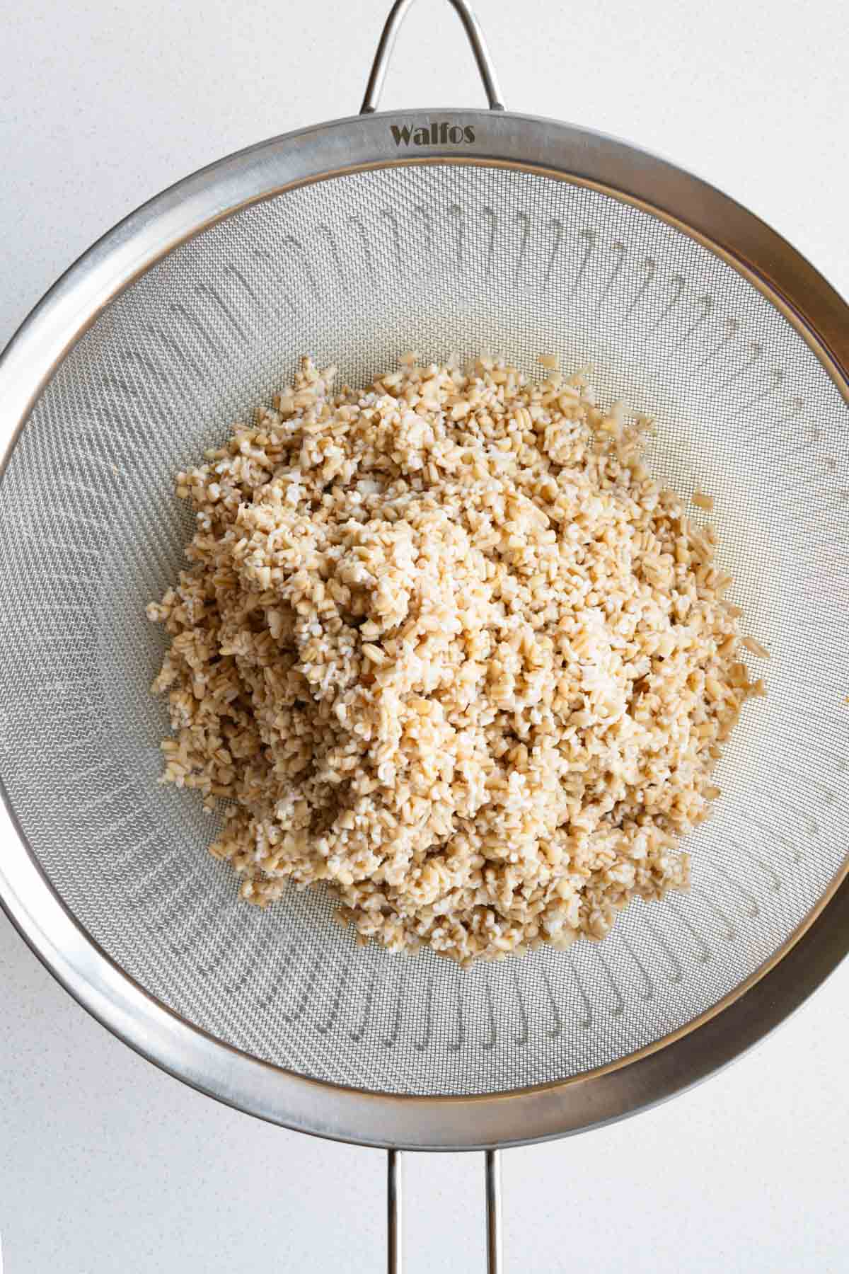 Drained soaked steel cut oats in a fine mesh sieve.