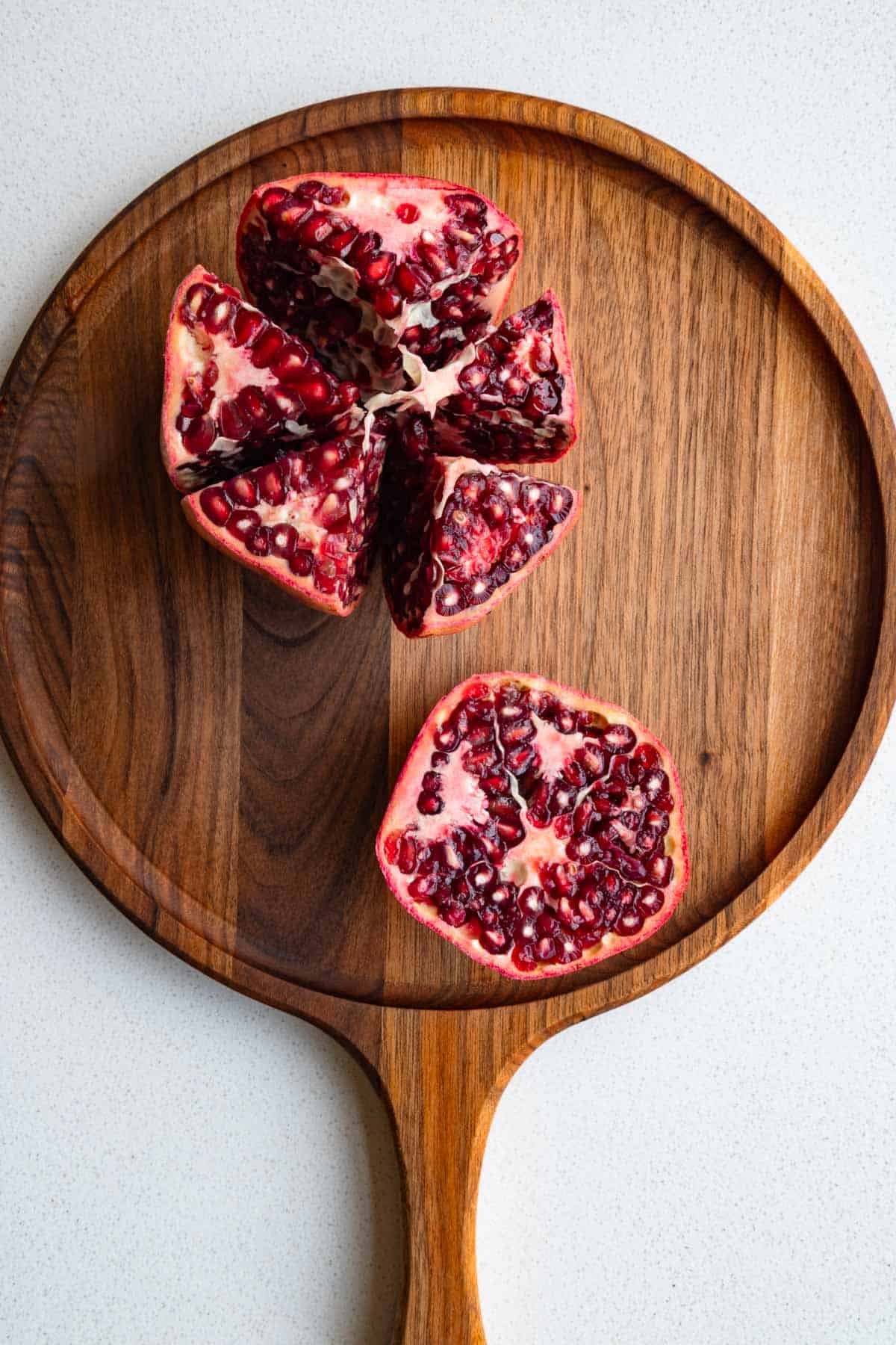 Sliced open pomegranate on a wooden cutting board.