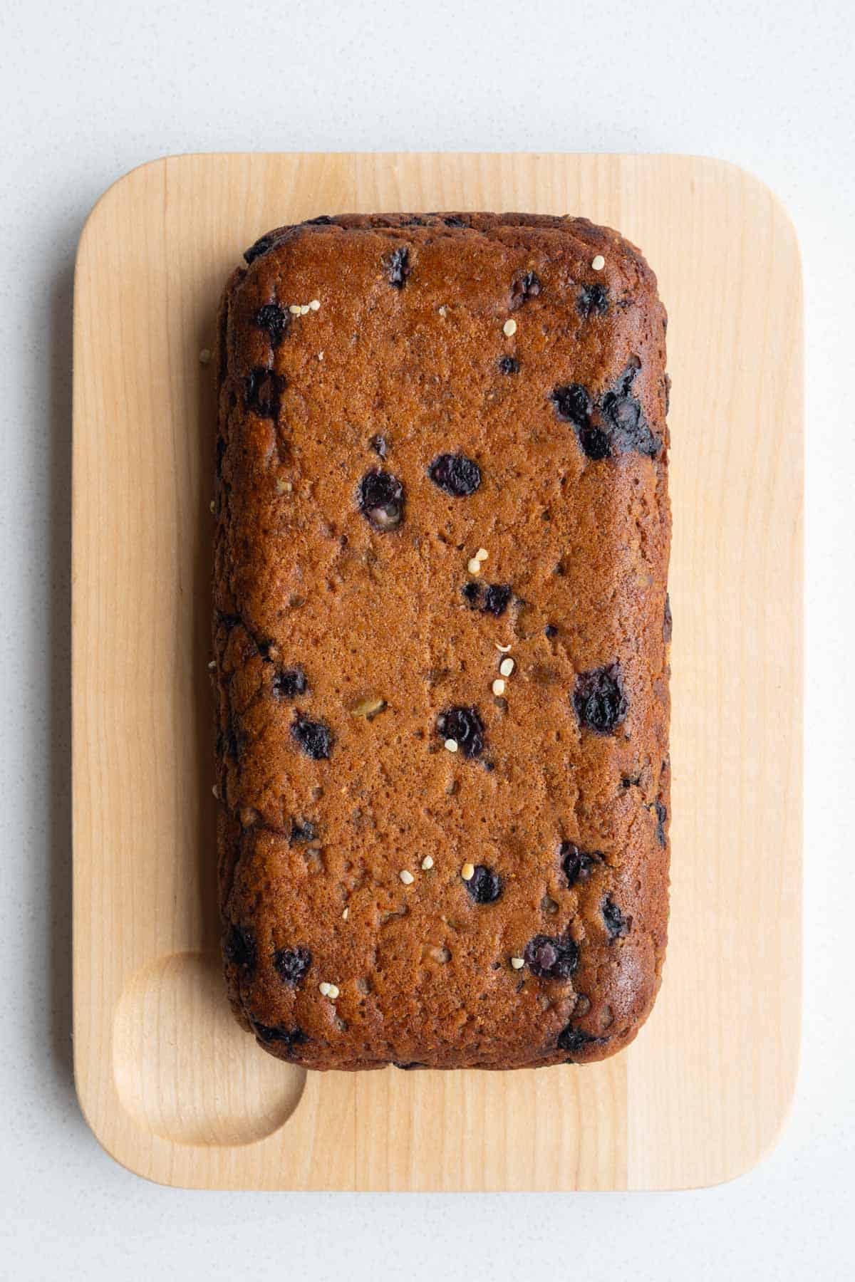 High-protein lemon blueberry loaf with chia seeds on a cutting board.