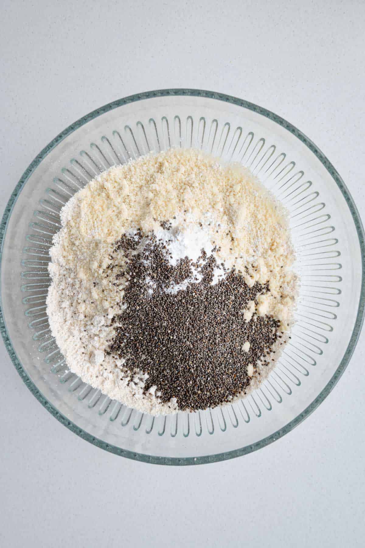 Almond flour, oat flour, baking powder, baking soda, and chia seeds in a glass bowl.