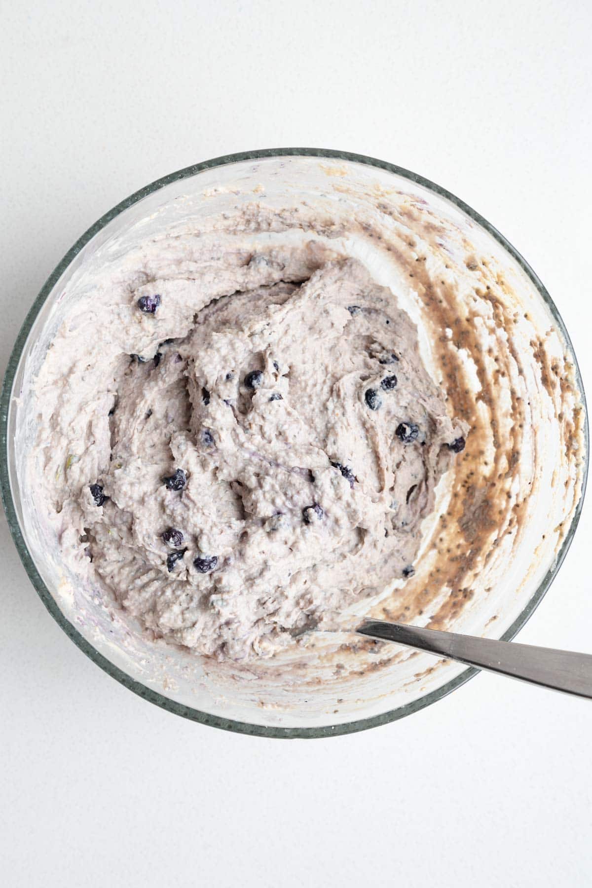 Healthy muffin batter with blueberries on a glass bowl.