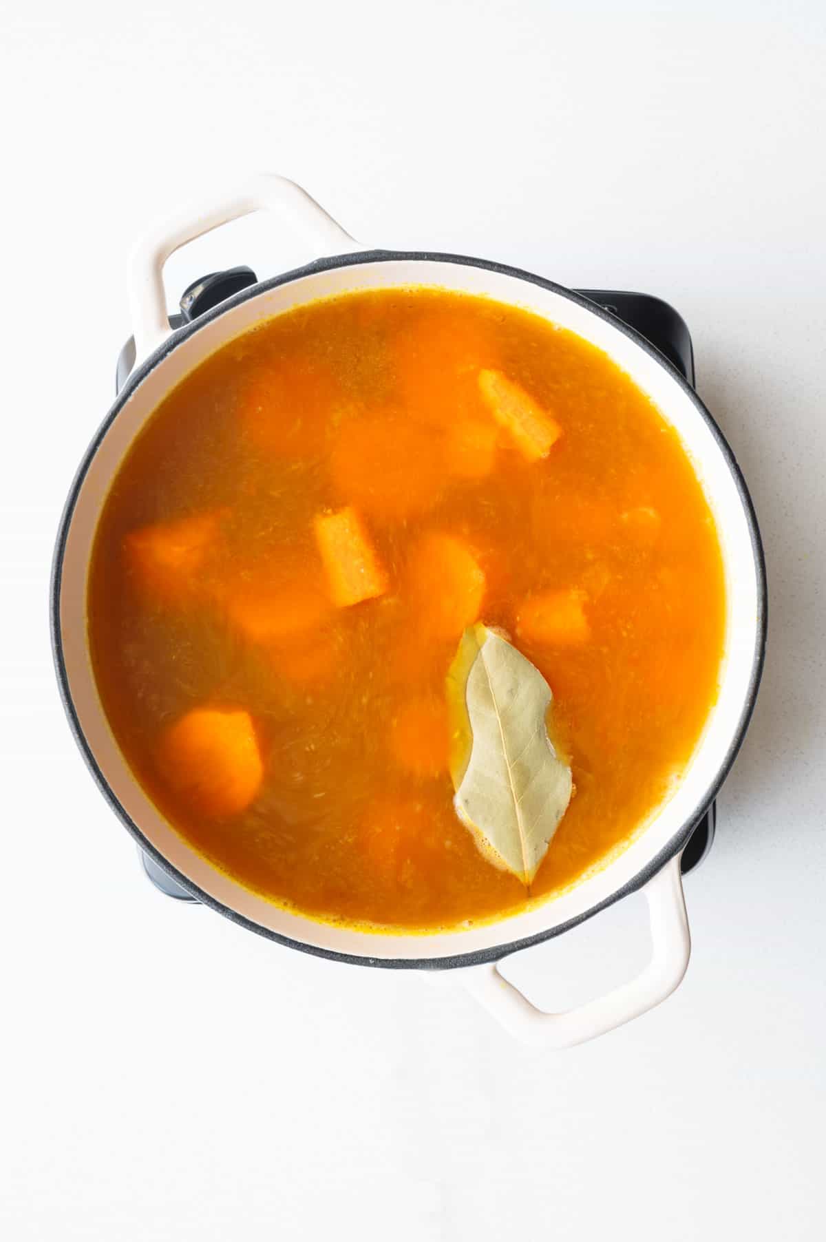 Red lentils, carrots, barley, seasoning, and aromatics in a saucepan.