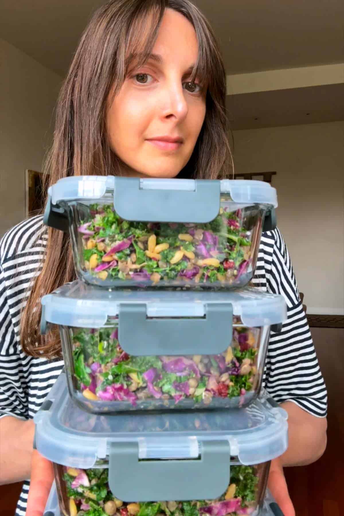 Nisha Melvani holding three containers of high-protein meal prep salads.
