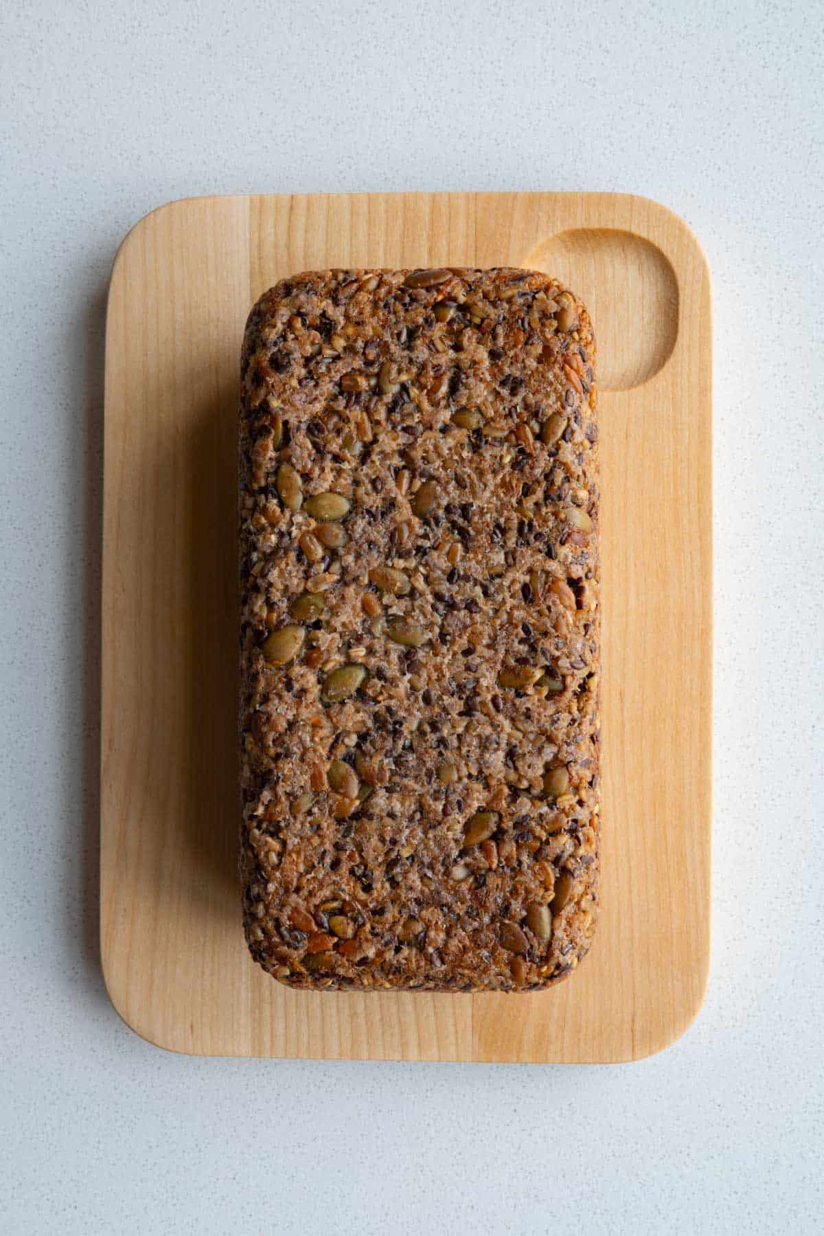Gluten-free homemade Seed Bread on a cutting board showing the base view.