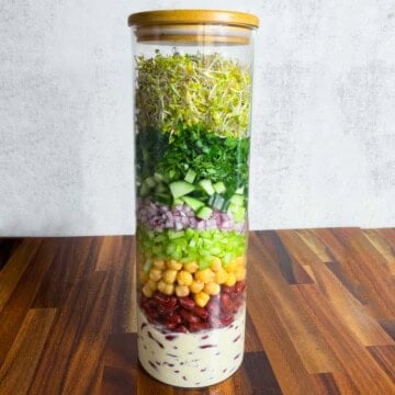Broccoli sprouts, red onion, cucumber, chickpeas, red kidney beans, parsley, coriander, and creamy lime miso dressing in a salad jar.