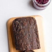 Black sesame cake sliced on a cutting board with chia jam.