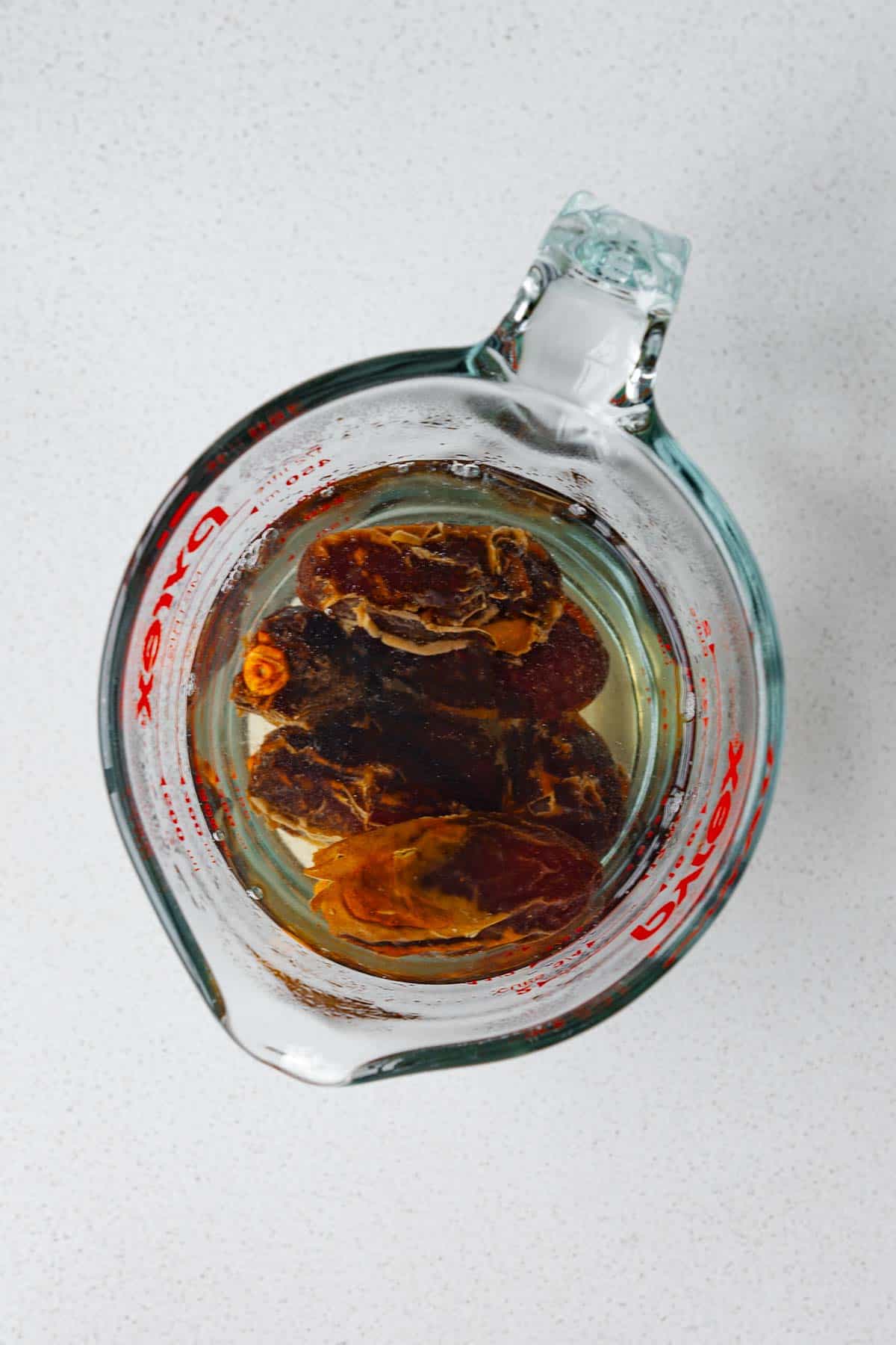 Soaked dates in a measuring cup with water.