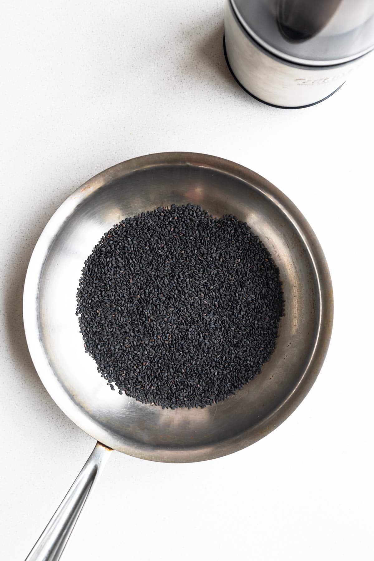 Toasted black sesame seeds in a skillet.