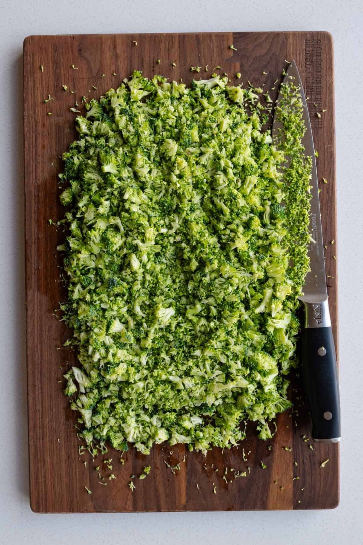 Chopped raw broccoli on a cutting board.