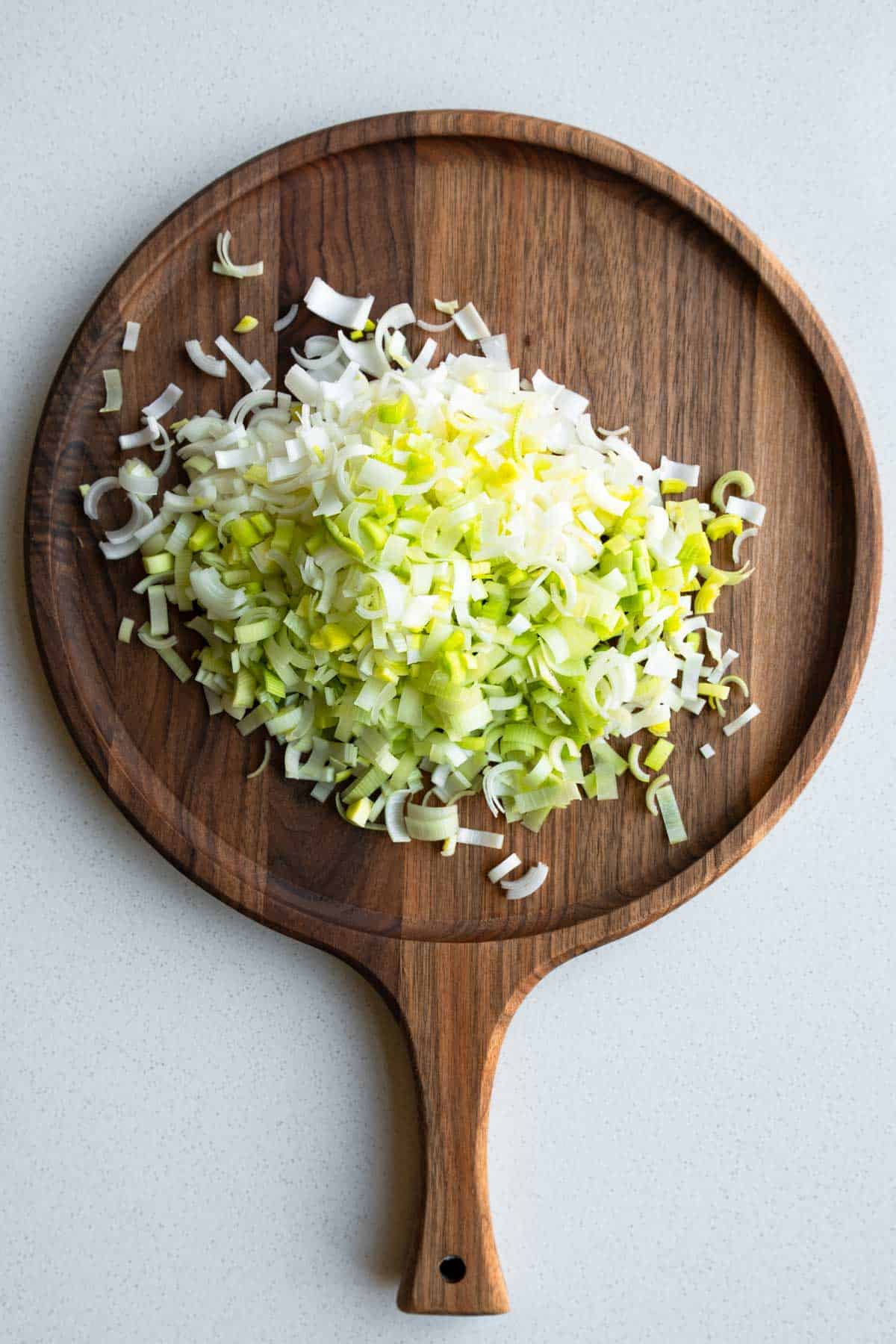 Chopped leeks on a wooden cutting board.