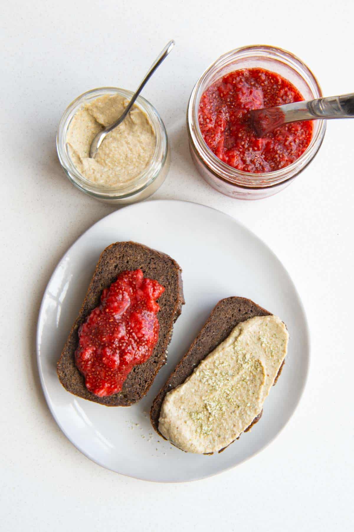 Healthy banana bread recipe sliced on a plate topped with chia jam and pumpkin seed cream.