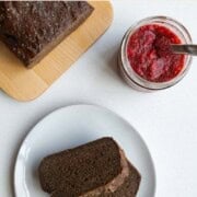 Healthy banana bread recipe sliced on a plate and on a cutting board with chia jam.