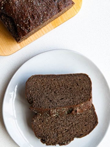 Healthy banana bread recipe on a cutting board and sliced on a plate.