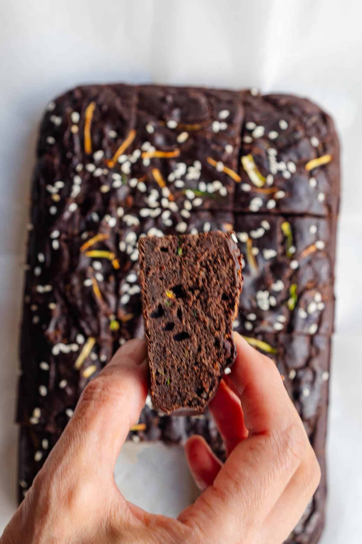 Healthy zucchini chocolate cake cut into squares on white parchment paper.