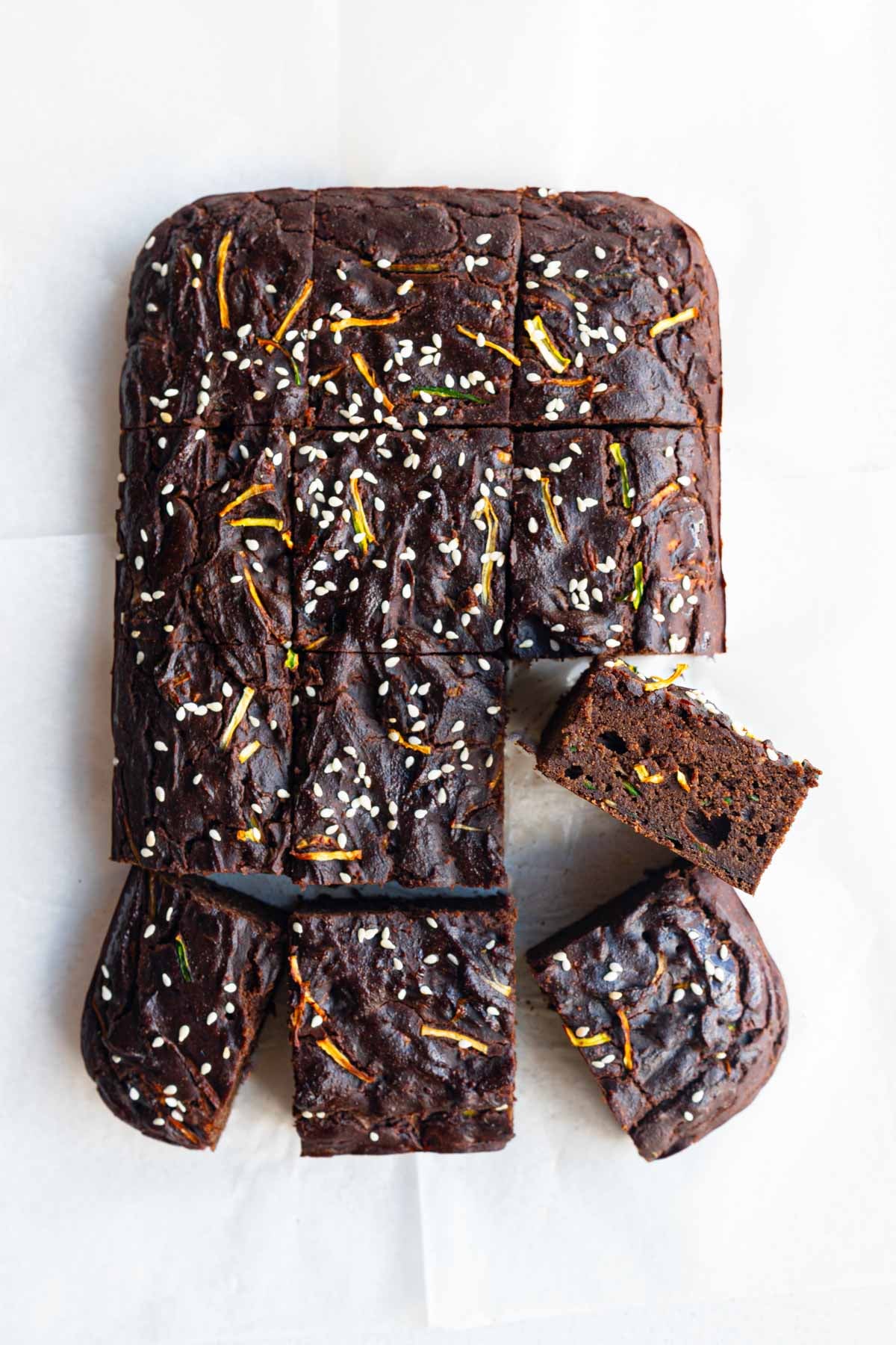 Healthy zucchini chocolate cake cut into squares on white parchment paper.