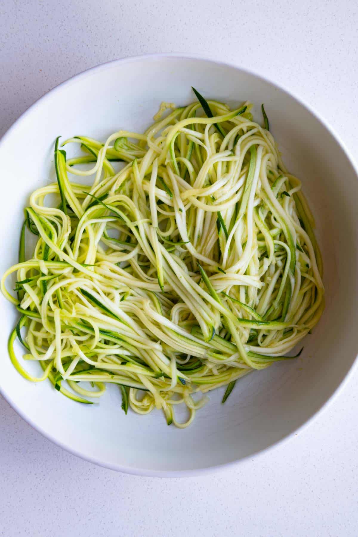 Julienned zucchini in a white bowl.