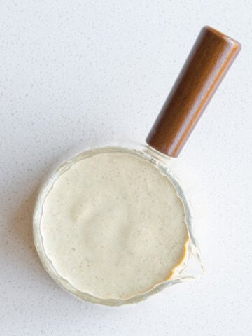 Pumpkin seed dressing in a glass container.