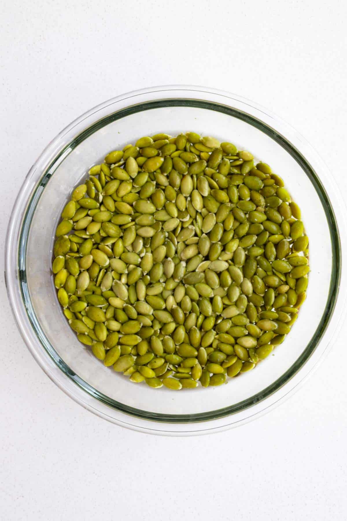 Pumpkin seeds soaking in water in a glass owl.