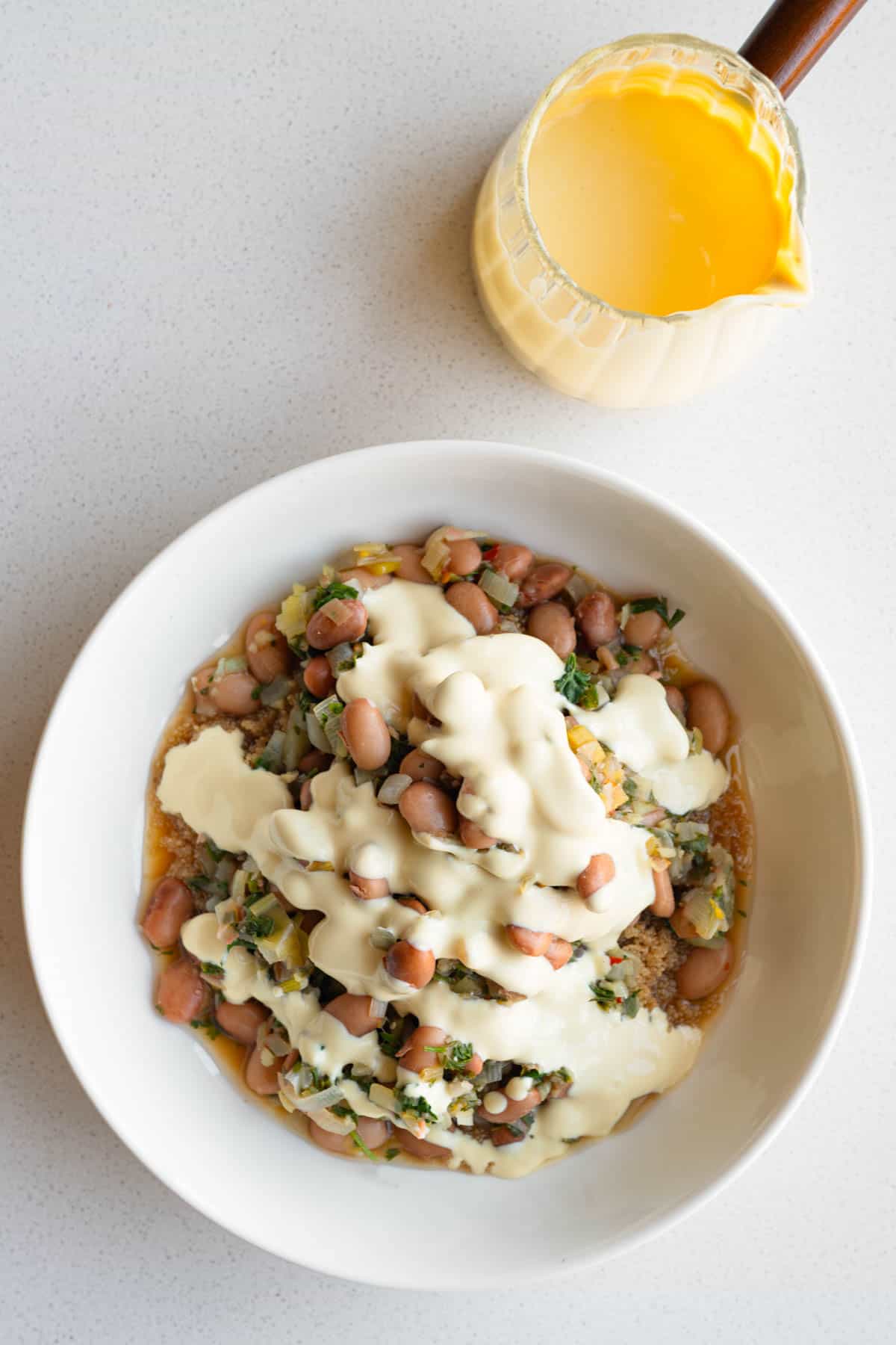 Brothy pinto beans with leeks and lemon topped with tofu cream.